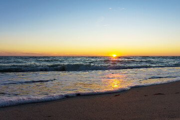 Sunset over the sea. Reflection of sunlight in the sea waves. The sky in the sunset rays.