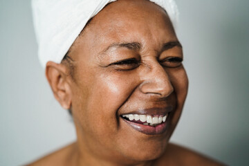 Senior african american woman having fun wearing towel on head at home spa - Focus on left eye