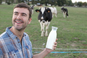 Farmer holding fresh milk with cows in the background