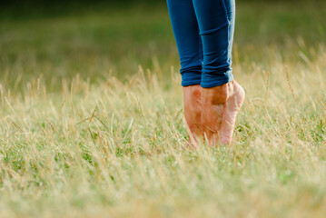 Closeup of woman with bare feet stretching muscles in summer park