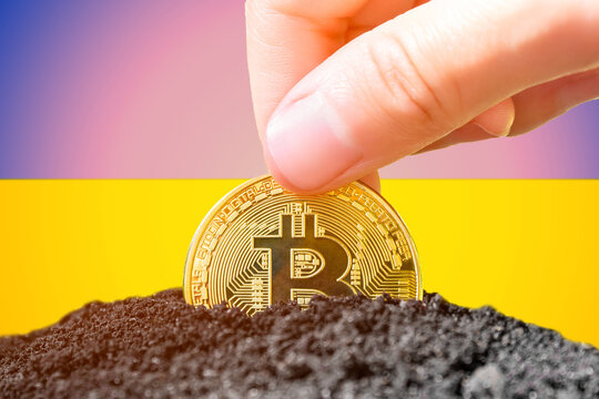 Legalization of bitcoin in Ukraine. Landing bitcoin in the ground against the background of the flag of Ukraine. Ukraine - investment in cryptocurrency.