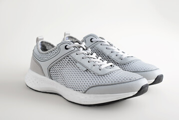 Pair of light-colored summer sneakers with cushioning and ventilation in the form of mesh, standing...