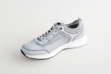 One new summer running shoe with mesh ventilation, side view. Sports stylish lifestyle sneaker on light background
