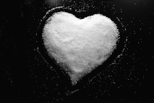 Abstract photo with image of heart made of white sugar on dark background as symbol of love