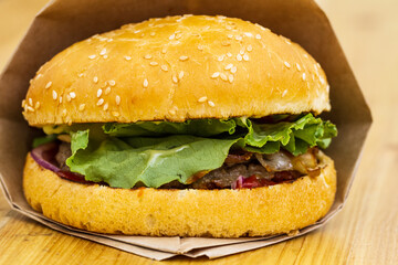 Close-up of a hamburger with yellow bun in a package on a wooden background