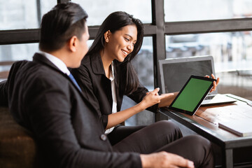 happy asian businessman and woman having a relaxed meeting using tablet in cafe