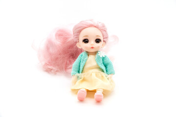 little plastic doll, baby girl. Little blonde doll with blue eyes on white bg. Isolated on white background with shadow reflection. With red shirt and checkered pants.