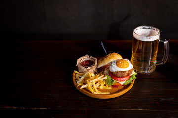 Hamburger. Sandwich with chicken burger, tomatoes, pickled cucumber and fried egg. Fresh tasty chicken burger on wooden table. beer