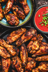 Grilled chicken wings on a black plate on a dark rustic background