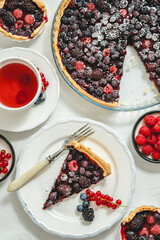 Delicious homemade piece on a plate and the whole homemade forest berry tart
