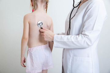 A pediatrician doctor listens with a stethoscope to the lungs of a child who has wheezing in the lungs. Bronchitis and pneumonia with colds and the virus in children, virus - obrazy, fototapety, plakaty