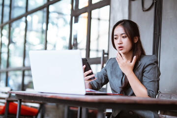 confused young businesswoman while using her mobile phone during working at the office