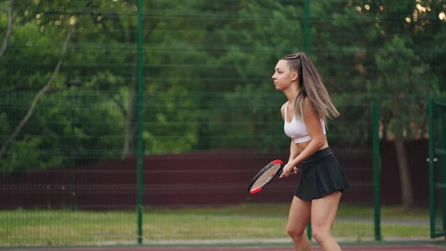 beginner tennis player woman is playing on outdoor court in summer day, training and preparing to competition