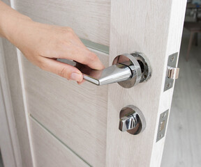 A man's hand opens an interior door with a broken doorknob. Poor quality door hardware, breakage,...