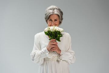 middle aged bride in white wedding dress holding bouquet isolated on grey