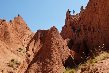 Silhouettes of two persons on top in Fairytale Canyon or Skazka Canyon, a colourful natural...