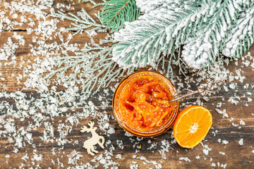 Organic orange jam with snow-covered fir branches. Seasonal food, handmade gift, traditional dessert