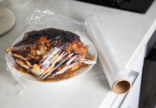 A Plate With Fried Chicken Wrapped In Cling Film In The Kitchen, Close-up. Keeping Food Fresh And Preventing Odor Absorption In The Refrigerator, Close-up