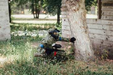 Paintball player hiding  behind the tree during the paintball game