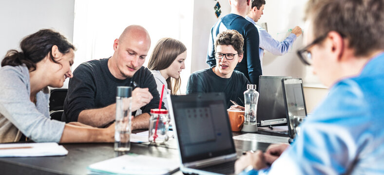 Startup business and entrepreneurship problem solving. Young AI programmers and IT software developers team brainstorming and programming on desktop computer in startup company share office space.