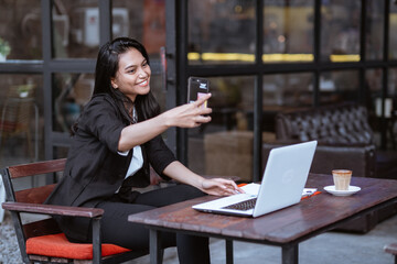 beautiful asian businesswoman having a video conference using smartphone while working at cafe