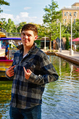 Handsome young man standing by a canal with the sun to his back confidently pointing at himself.