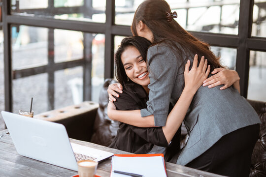 beautiful female worker greeting and hug her partner while meeting at the office