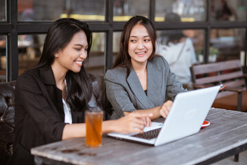 portrait of two businesswoman asian talking while enjoying coffee and working