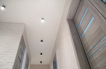 Fototapeta premium Modern renovation and design in the hallway. Black LED spotlights on the ceiling. New gray interior doors.