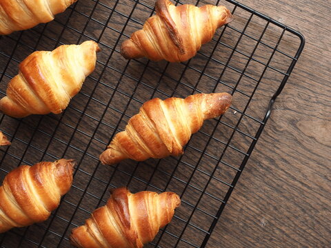Top view small french butter croissants on baking rack on wooden background
