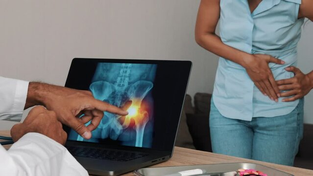 Doctor showing x-ray of pain in the side of hips on a laptop with woman patient