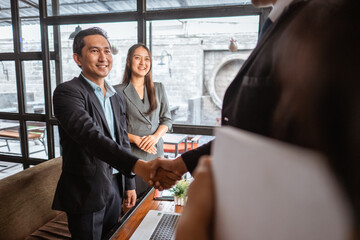 happy two young business partner and executive shaking hands in the cafe