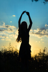 Silhouette of a dancing girl on the background of the sunset, blue and yellow