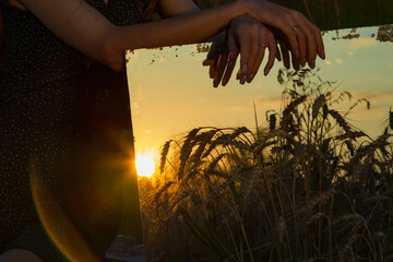 female hands on the mirror, reflection of wheat at sunset, healthy organic nutrition