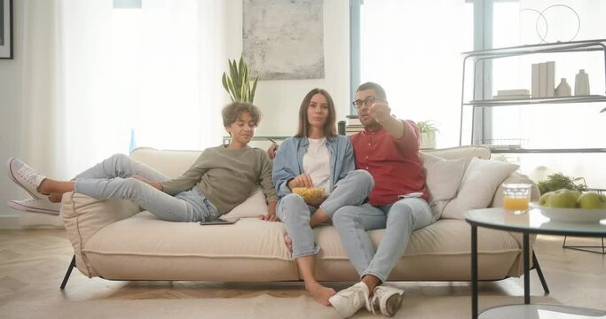 Happy family watches comedy with popcorn sitting on couch