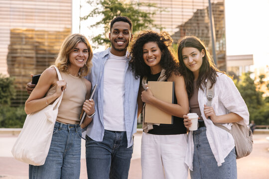 Group of young multiethnic friends smiling looking at camera posing outdoors. Guy with girls wear casual clothes in spring. Real emotions concept