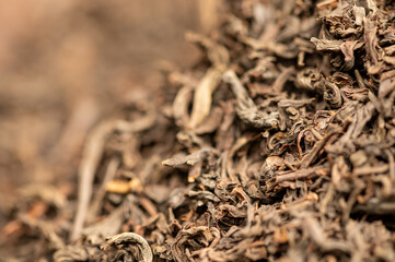 Large-leaf black tea in a glass and scattered on the table. Close-up of the surface texture