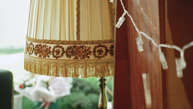 Vintage style floor lamp torchere with bell shape fringed drapery shade being switched on and off by pulling a chain, slow motion.