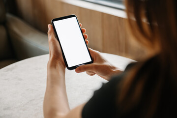 woman holding smart phone and digital tablet with blank white desktop screen in cafe.