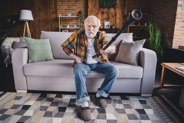 Obraz premium Photo of angry furious retired man dressed plaid shirt sitting couch rising nursery cane indoors apartment