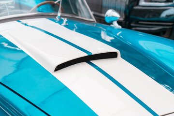 The hood of a retro muscle car with air intake slots for a turbocharged powerful engine
