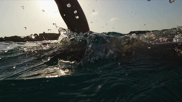 Athletic Young man professional triathlon swimmer practicing at morning sea. Ocean swim slow motion shot