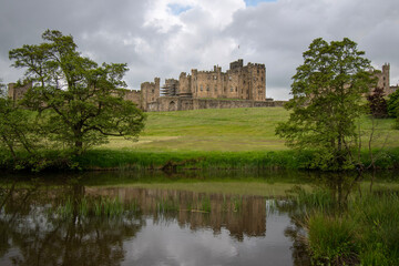 Fototapeta na wymiar Alnwick Castle reflected in the water of the River Aln. Northumberland, UK