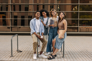 Fototapeta na wymiar Full length young interracial students posing looking at camera standing on street near college. Guy and girl wear light clothes in spring. Good mood concept