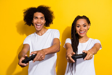 Photo of two excited crazy people hands hold controllers play games isolated on yellow color background © deagreez