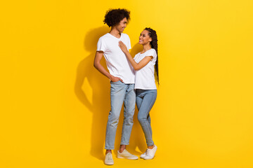 Full length photo of two cheerful lovely partners cuddle look each other isolated on yellow color background