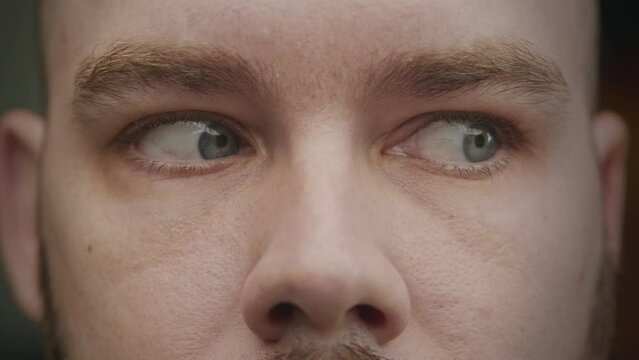 Close up shot of caucasian adult man blue eyes looking from side to side