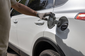 man opens the hatch of the gas tank of the car