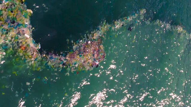 Vertical shot of plastic bags and rubbish floating in sea waters. Aerial