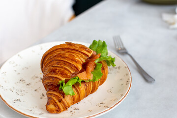 Delicious and healthy breakfast croissant with salmon lettuce and cream cheese on a plate